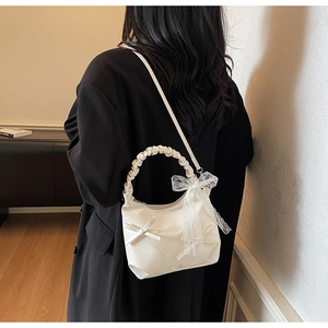 Detail of ruched handle on off-white cloud bag with lace bow and ribbon accents
