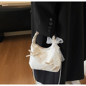 Détail d'un sac à main blanc style ballet avec nœud et ruban en dentelle sur un manteau