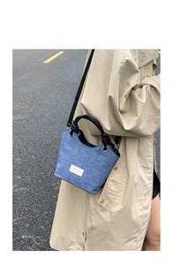 Detalle del bolso de hombro vaquero con asa circular negra y etiqueta de marca blanca