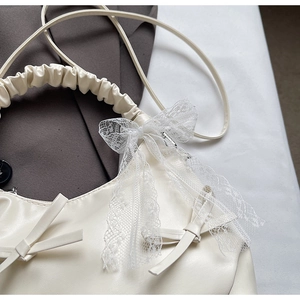 Vue détaillée du sac à main blanc crème avec nœud en dentelle et poignée froncée
