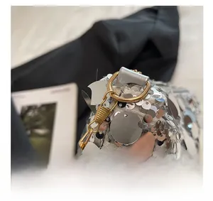Detail shot of silver sequin handbag featuring gold-plated hook and metal chain strap