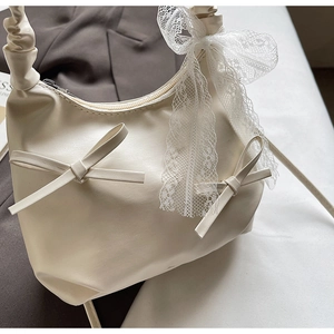 Détail du grand nœud en dentelle sur la bandoulière du sac à main couleur crème