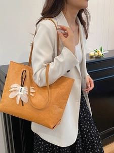 Chic orange large capacity tote bag with white flower pendant for autumn 2025 fashion