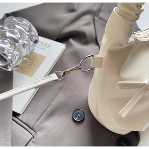 Détail du sac en cuir blanc crème montrant le fermoir mousqueton argenté et le nœud