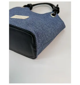 Dettaglio degli angoli in pelle rinforzata e della trama in denim di questa borsa a spalla
