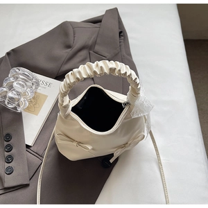 Détail du sac crème style balletcore avec nœuds décoratifs et poignée froncée