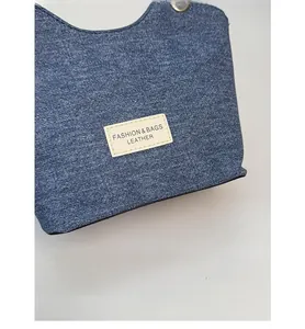 Dettaglio macro della trama in denim blu e della toppa in pelle sulla borsa a tracolla alla moda