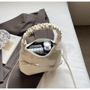 Détail du sac à main blanc crème avec nœuds, dentelle et rangement intérieur pratique