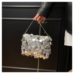 Close-up of sparkling silver sequins and gold chain strap on stylish shoulder bag