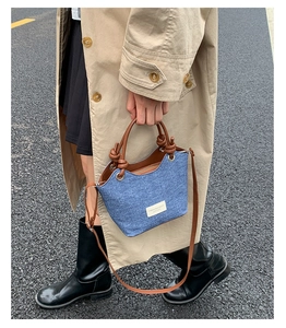 Dettaglio borsa a secchiello in denim blu con cinturini in pelle marrone stile urban