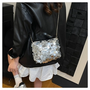 Detail of silver sequined crossbody bag with gold chain strap on a fashion model