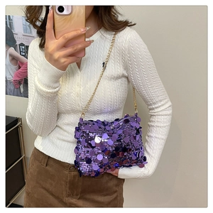 Close-up of a women's purple sequin handbag with a gold metal chain strap on a model