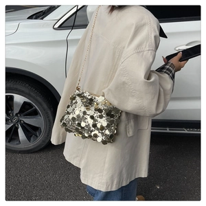 Detail of sequined shoulder bag with gold chain strap on a model in street setting