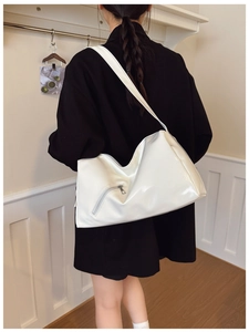 Close-up of white glossy tote bag with silver zipper detail on a black blazer