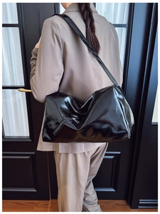Close-up of the glossy black patent leather finish and functional zipper detail on the bag