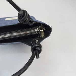 Dettaglio della borsa a tracolla blu testurizzata con zip metallica e manico in pelle annodato