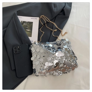 Close-up of silver sequin shoulder bag with elegant gold chain strap and luxury texture