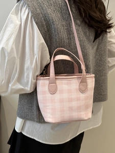 Pink and white checkered mini handbag with crossbody leather strap on a model