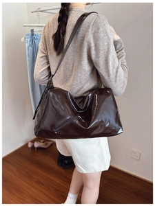 Detailed side view of large caramel brown tote bag with high-gloss finish and side zipper