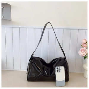 Glossy black hobo bag size comparison with smartphone on white striped background