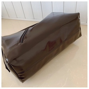 Detail view of large glossy brown handbag showing smooth leather texture and side zipper
