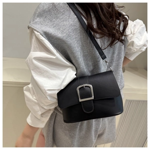 Detail of minimalist black matte leather crossbody bag with silver square buckle close-up