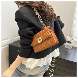 Detail der gesteppten braunen Ledertasche mit goldener Hufeisenschnalle am Modell