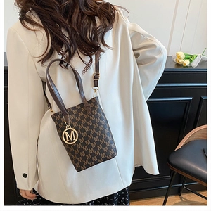 Close-up of vintage monogram tote bag with gold M-shaped metal charm and brown leather handles