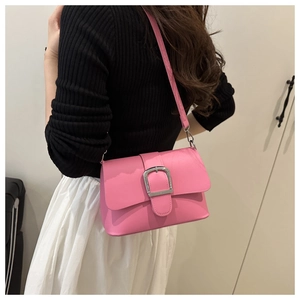 Detail of pink faux leather crossbody bag featuring a silver U-shaped metal buckle clasp