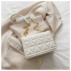 Nahaufnahme der weißen gesteppten Handtasche mit goldener Kette auf einem Blazer