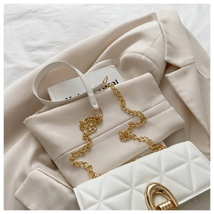 Detail der weißen Stepptasche mit Goldkette und Ovalschloss auf beigem Blazer