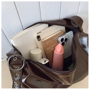 Detail of spacious dark brown patent leather tote interior holding a tablet and books