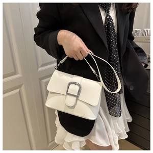 Minimalist beige handbag with adjustable strap and silver metal buckle worn by a model