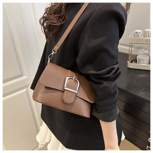 Gros plan d'un sac bandoulière marron vintage avec boucle de ceinture en métal argenté