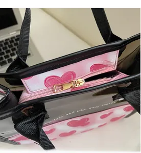 Dettaglio della borsa rosa con cuori, cerniera dorata liscia e manici neri