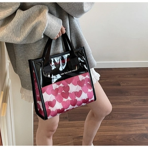 Detail view of heart-print tote bag with transparent PVC top and sturdy black handles
