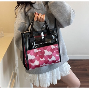Detail of transparent PVC tote bag with pink heart pattern and black fabric handles