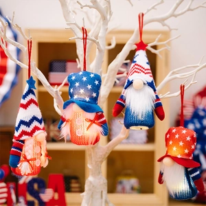Close-up of four lighted patriotic gnome ornaments with stars and stripes hanging on a branch