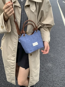 Borsa a secchiello in denim blu con tracolla in pelle marrone indossata da una modella