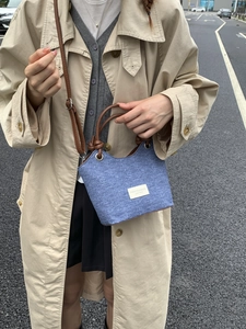 Borsa a secchiello in denim blu con manici in pelle marrone e tracolla regolabile
