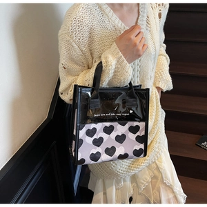 Detail of translucent heart print tote bag featuring a black PVC top and woven handles