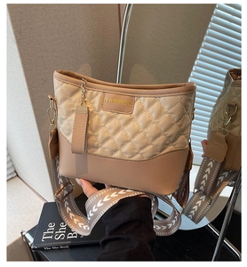 Close-up of quilted beige shoulder bag with gold Fashion logo and geometric strap