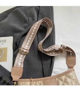 Detail of quilted crossbody bag featuring ethnic wide strap and fashion brand label