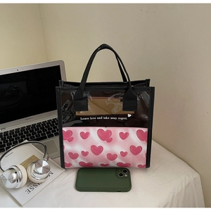 Detail of translucent heart print tote bag on desk with laptop and headphones
