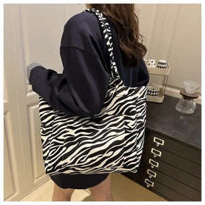 Detail of zebra print canvas tote bag featuring a front pocket and large capacity