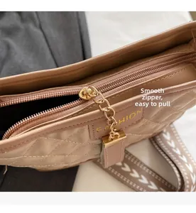 Close-up of smooth gold zipper and arrow pattern strap on beige quilted crossbody bag
