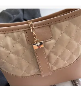 Detailed close-up of khaki quilted faux leather texture with elegant gold chain accents
