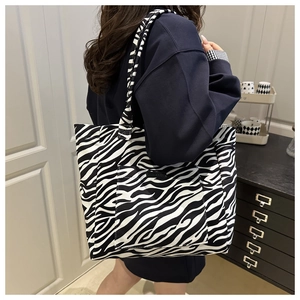 Detailed view of the zebra print canvas tote bag with shoulder straps and front pocket