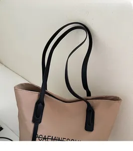 Gros plan des bandoulières noires et des coutures renforcées sur un grand sac fourre-tout