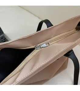 Détail de la fermeture éclair métallique lisse et du curseur argenté du sac beige